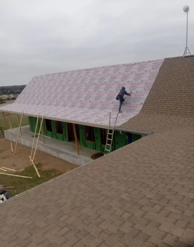 Worker preparing underlayment for a metal roof installation in Randallstown
